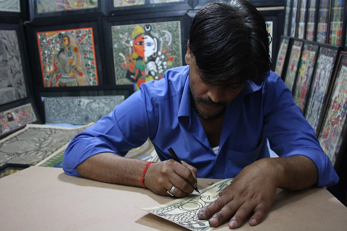 A Madhubani artist painting a traditional Mithila artwork at Dilli Haat crafts market