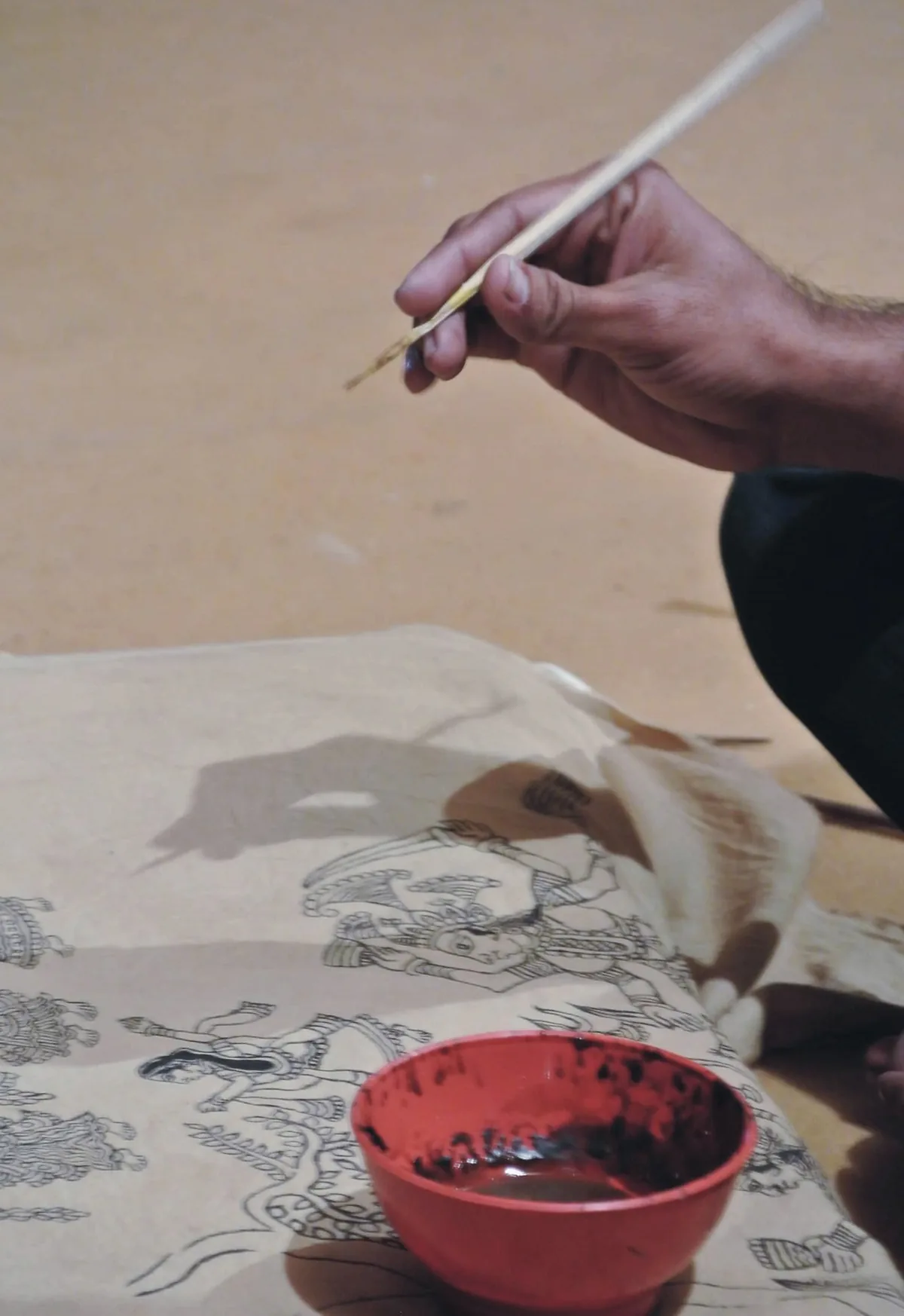 A Kalamkari artist hand-painting a textile with a bamboo pen in Sri Kalahasti